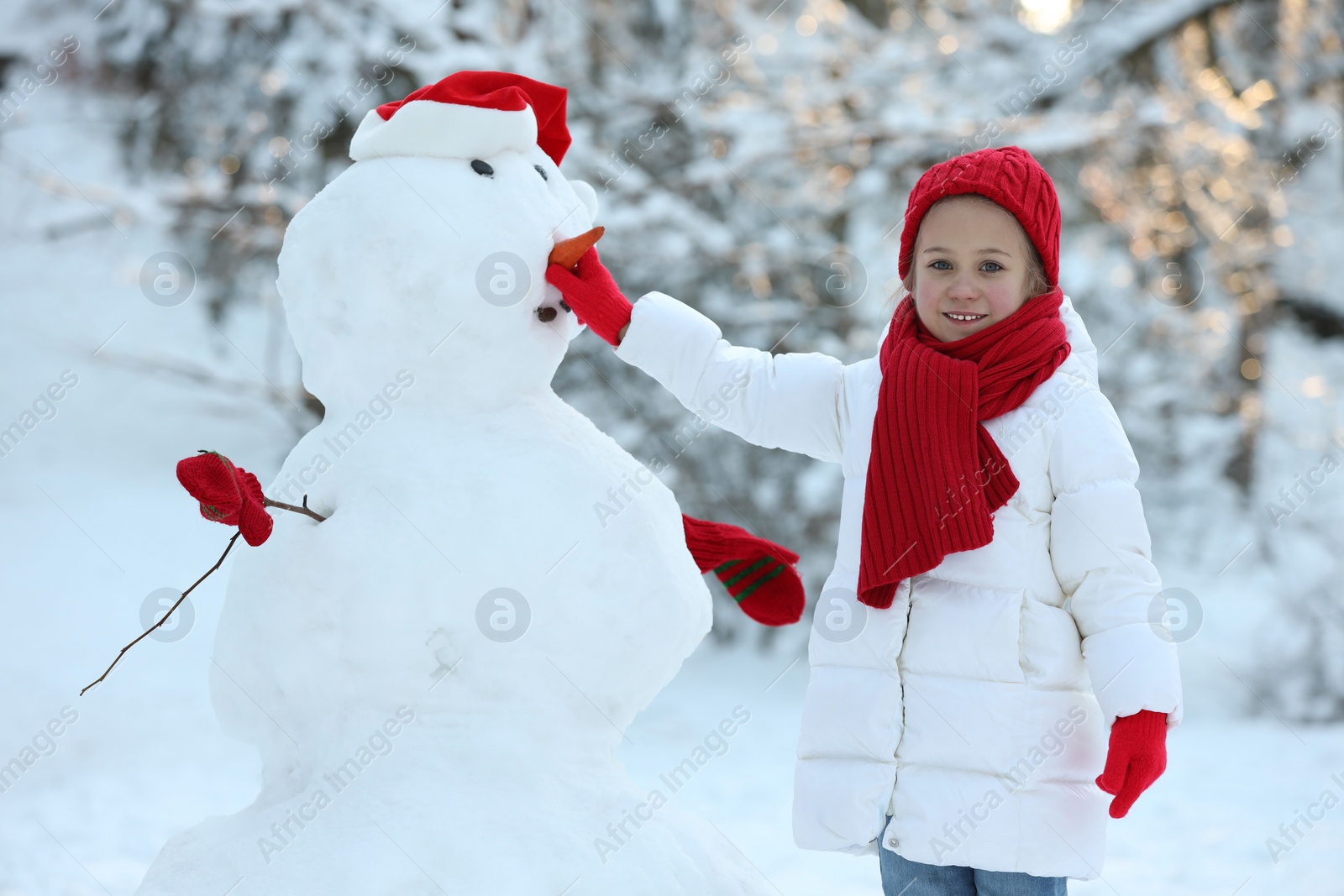 Photo of Cute little girl making snowman in winter park