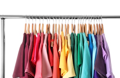 Photo of Rack with rainbow clothes on light background