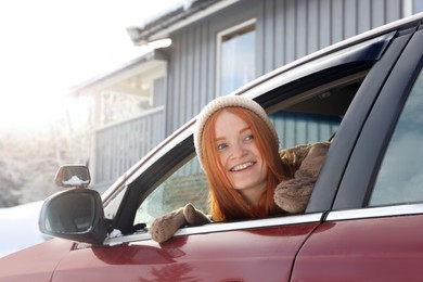 Photo of Happy young woman looking out of car window. Winter vacation