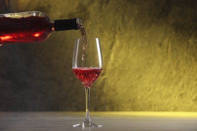 Photo of Pouring red wine from bottle into glass on table, space for text