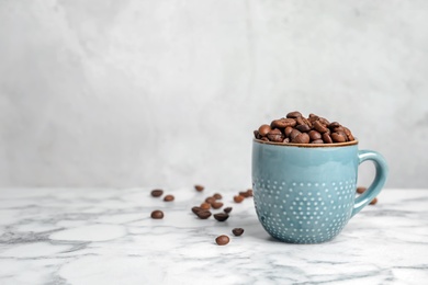 Ceramic cup with coffee beans on marble table