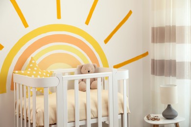 Photo of Baby room interior with crib near decorated wall