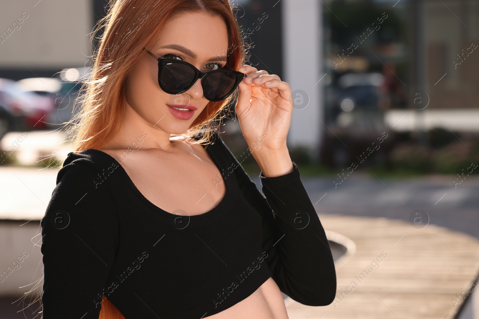 Photo of Beautiful woman in sunglasses on city street, space for text