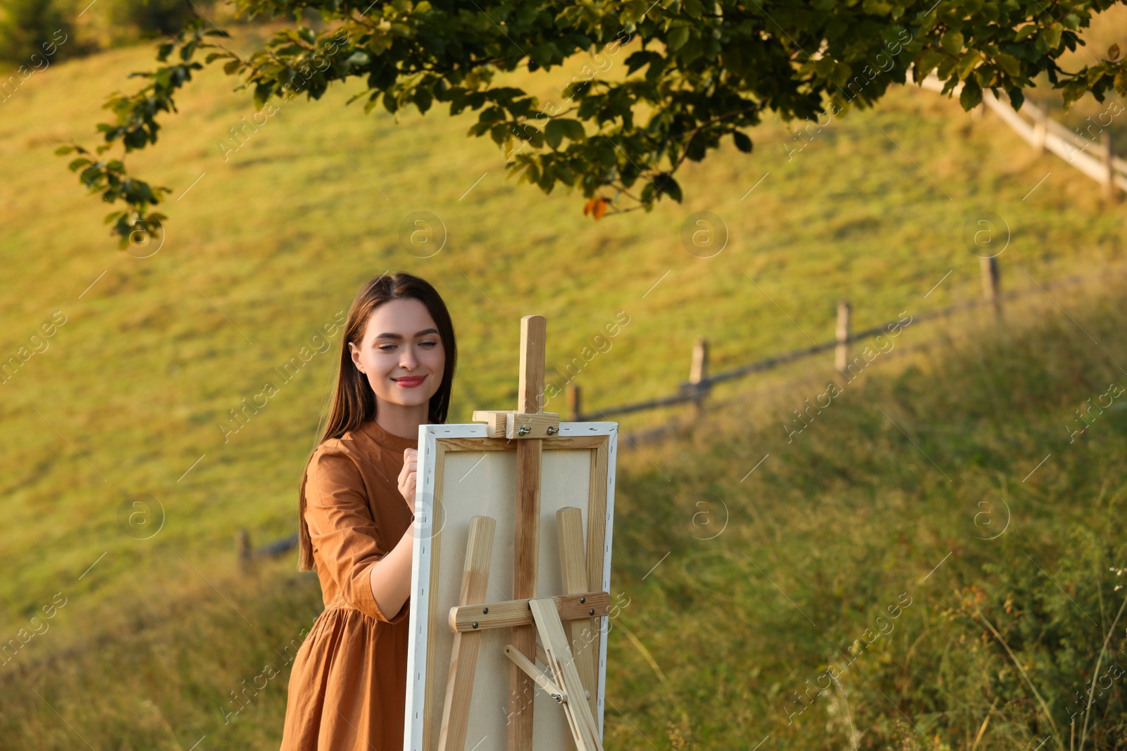 Photo of Beautiful young woman drawing on canvas in nature