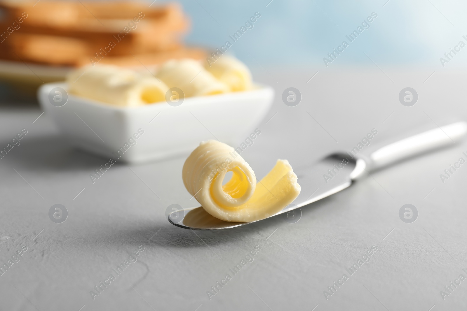 Photo of Knife with fresh butter curl on table