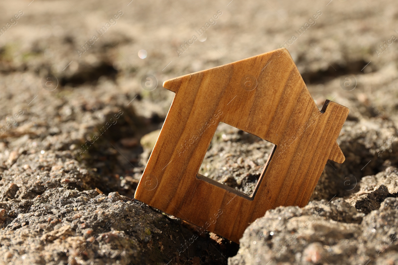 Photo of Wooden house model in cracked asphalt. Earthquake disaster