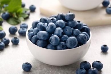 Photo of Tasty fresh blueberries on light grey table, closeup
