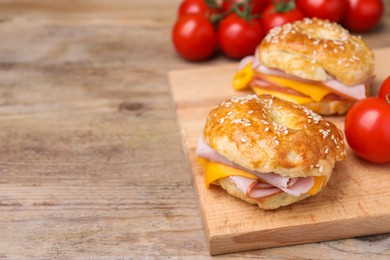 Photo of Delicious bagels with ham and cheese on wooden table. Space for text