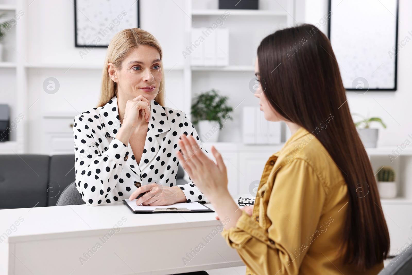 Photo of Psychologist working with teenage girl at table in office