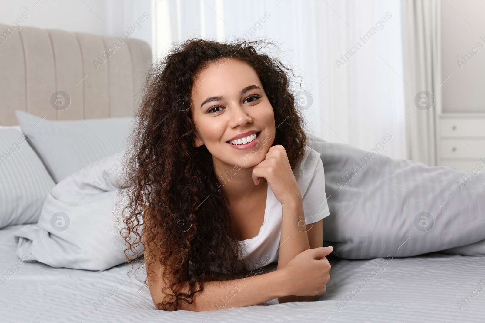 Photo of Happy beautiful African American woman lying in bed at home