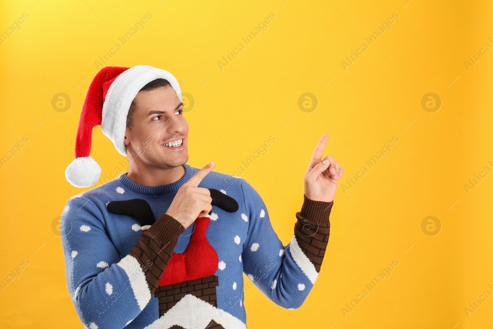 Photo of Handsome man wearing Santa hat on yellow background, space for text