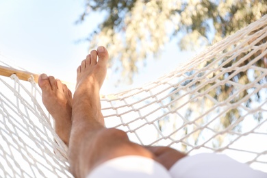 Photo of Man relaxing in hammock outdoors on sunny day, closeup. Summer vacation