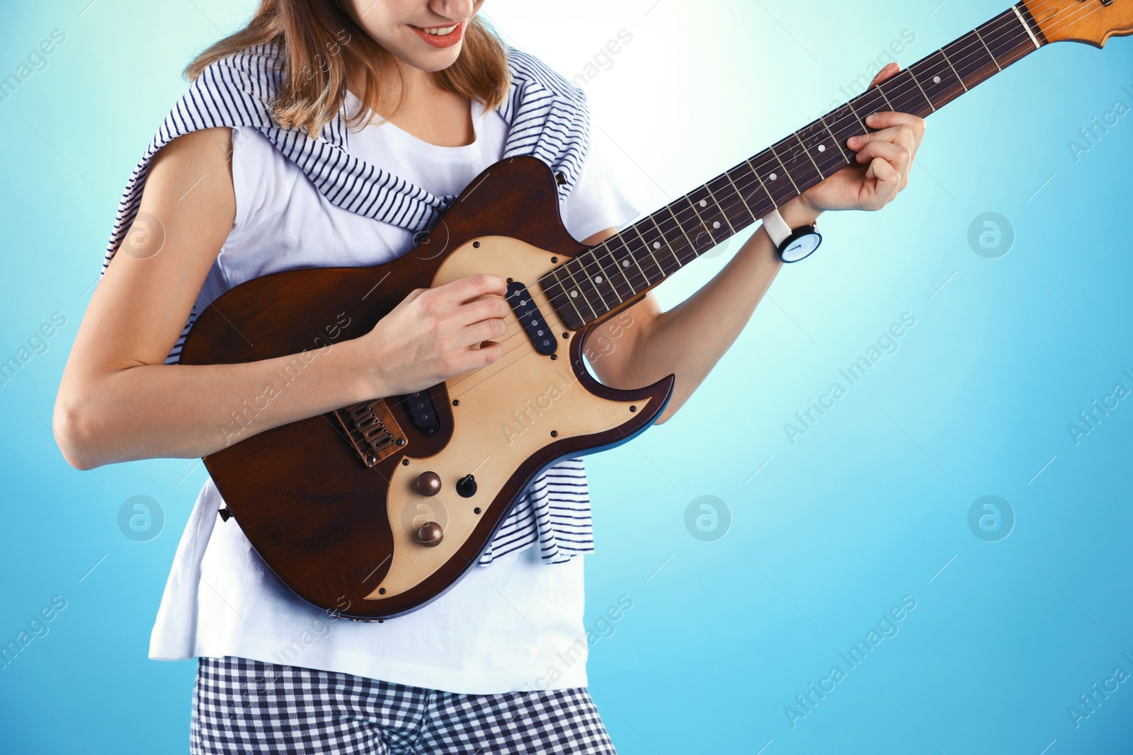 Photo of Young woman playing electric guitar on color background, closeup