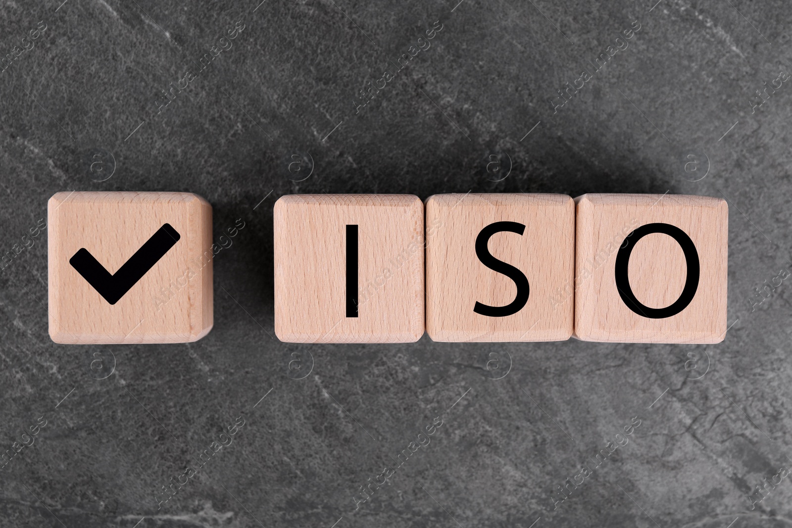 Photo of Cubes with check mark and abbreviation ISO on gray textured table, top view