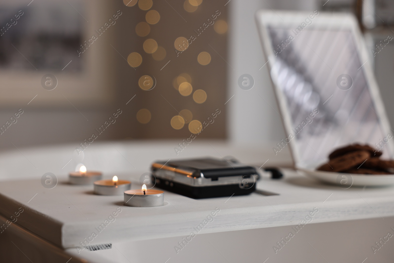 Photo of White wooden tray with cassette player and burning candles on bathtub in bathroom