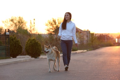 Photo of Young woman walking her adorable Akita Inu dog outdoors