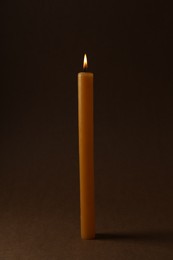 Photo of Burning church wax candle on dark background