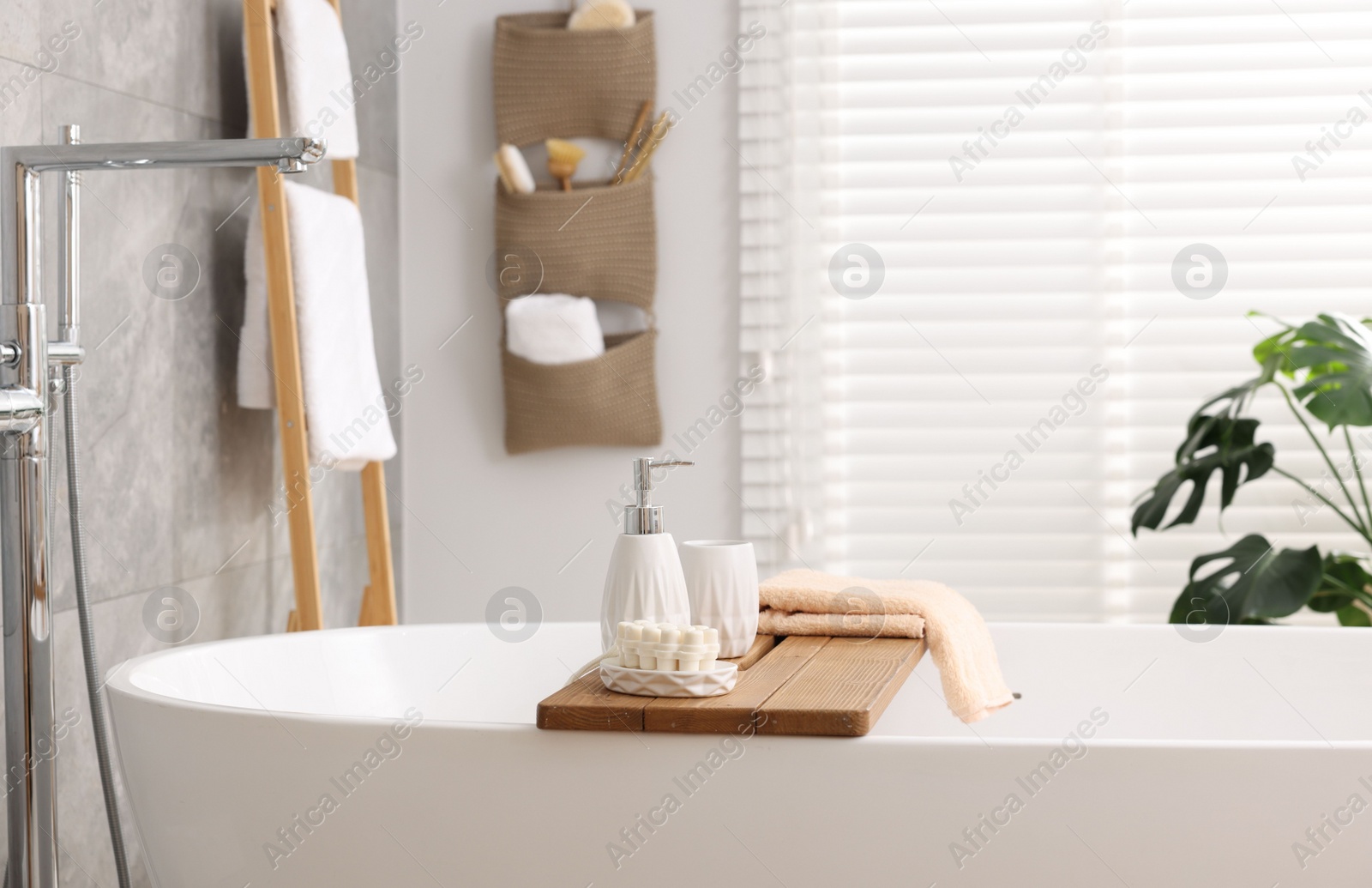 Photo of Set of different bath accessories and soap on tub in bathroom