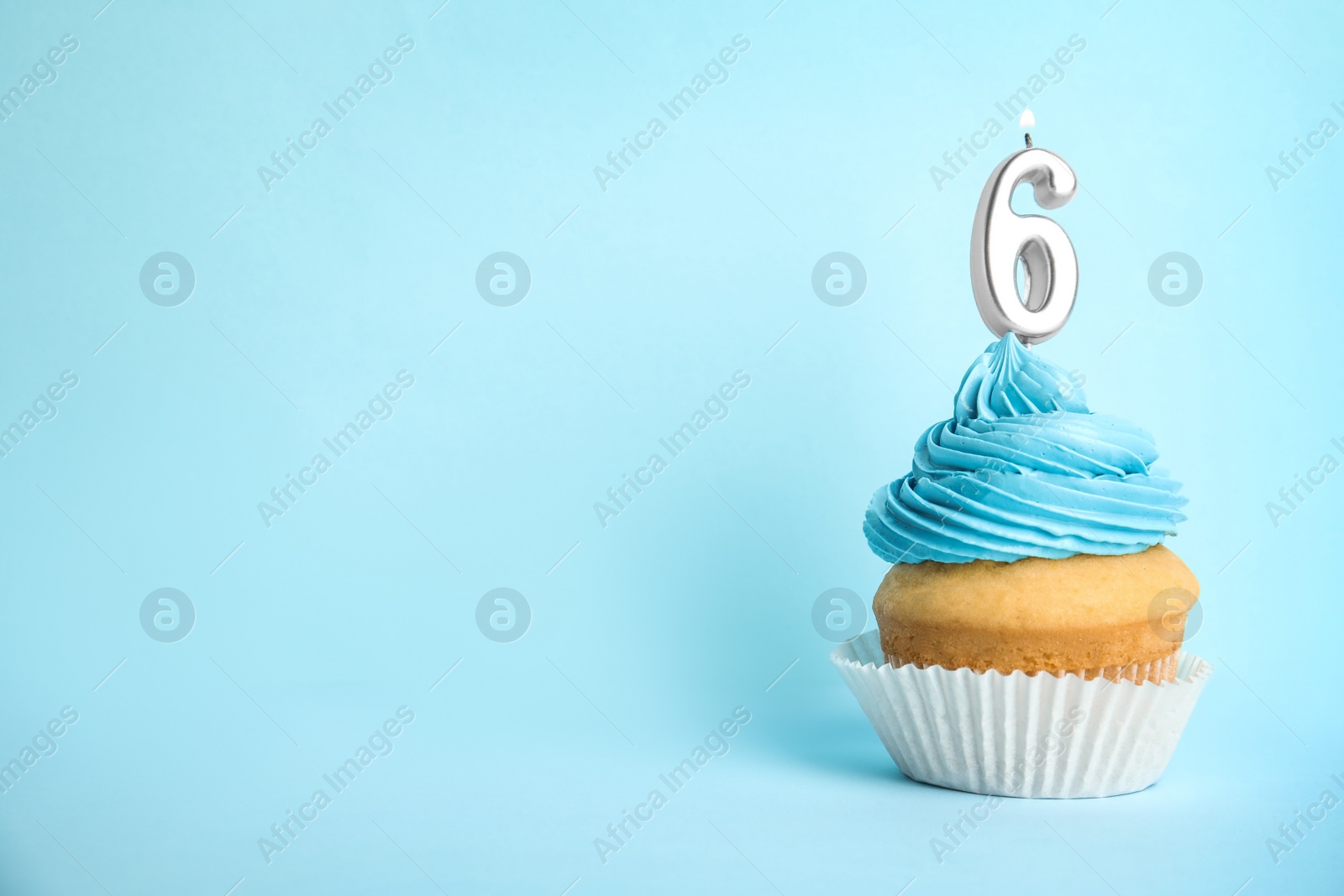 Photo of Birthday cupcake with number six candle on blue background, space for text