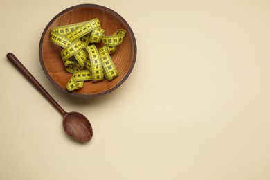 Photo of Measuring tape and wooden spoon on beige background, flat lay with space for text