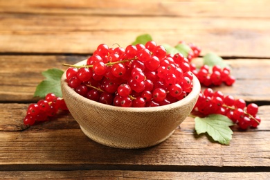 Photo of Ripe red currants in bowl on wooden table