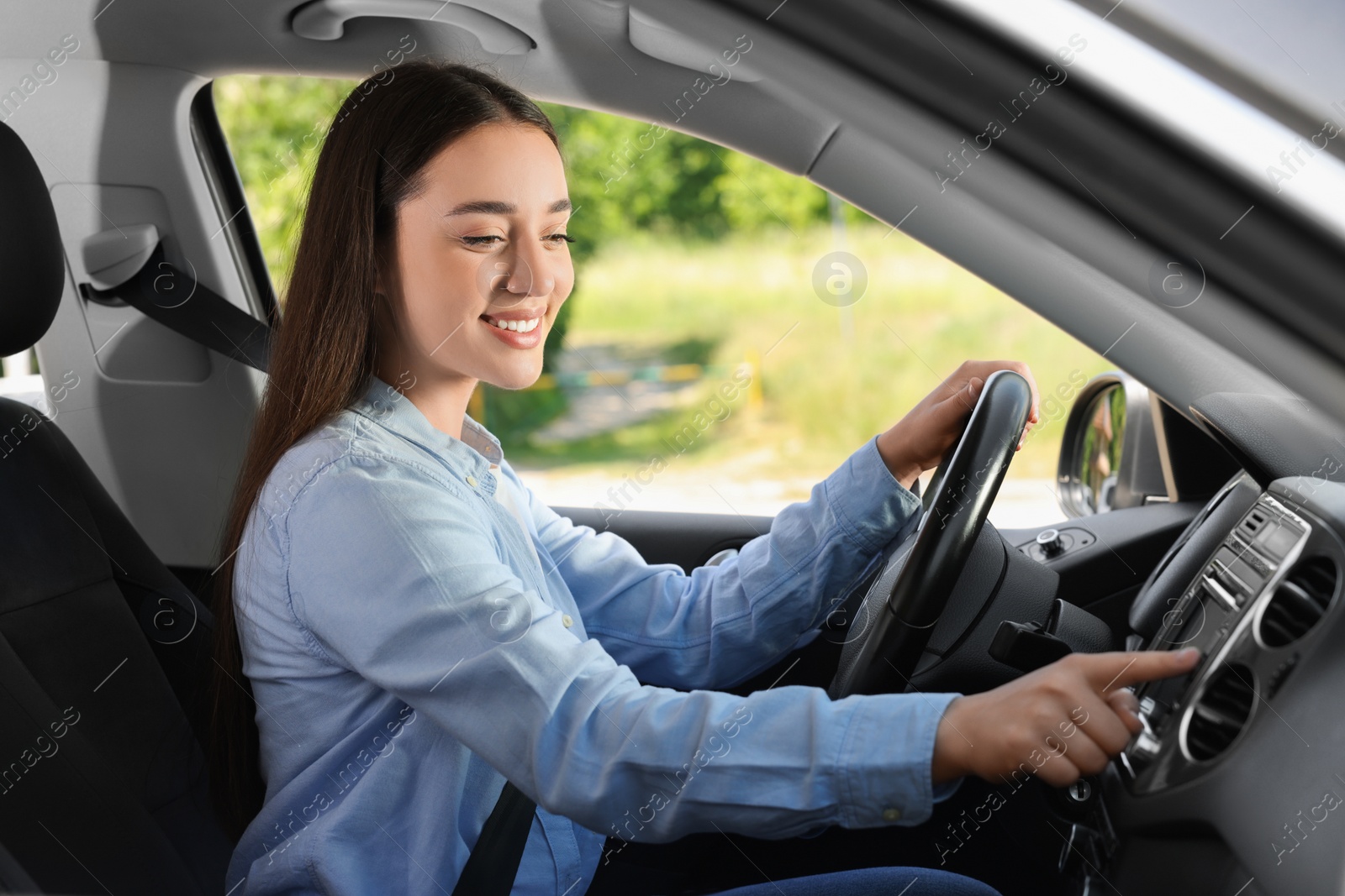 Photo of Choosing favorite radio. Beautiful young woman pressing button on vehicle audio in car