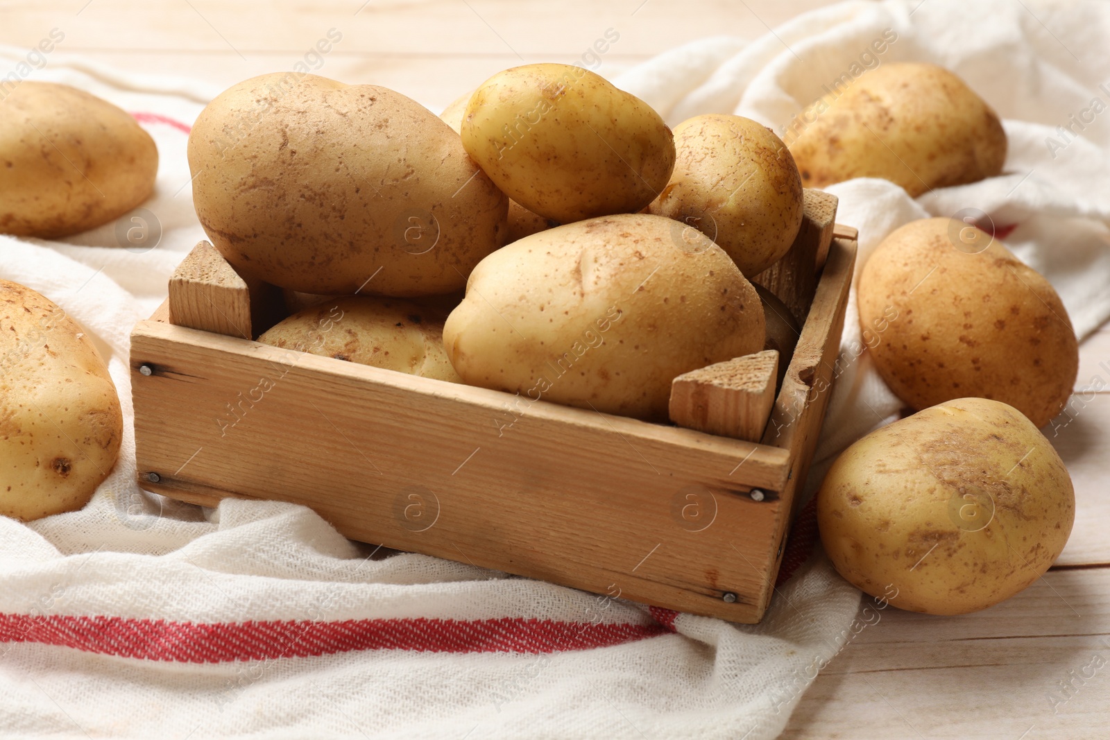 Photo of Raw fresh potatoes with crate on light wooden table