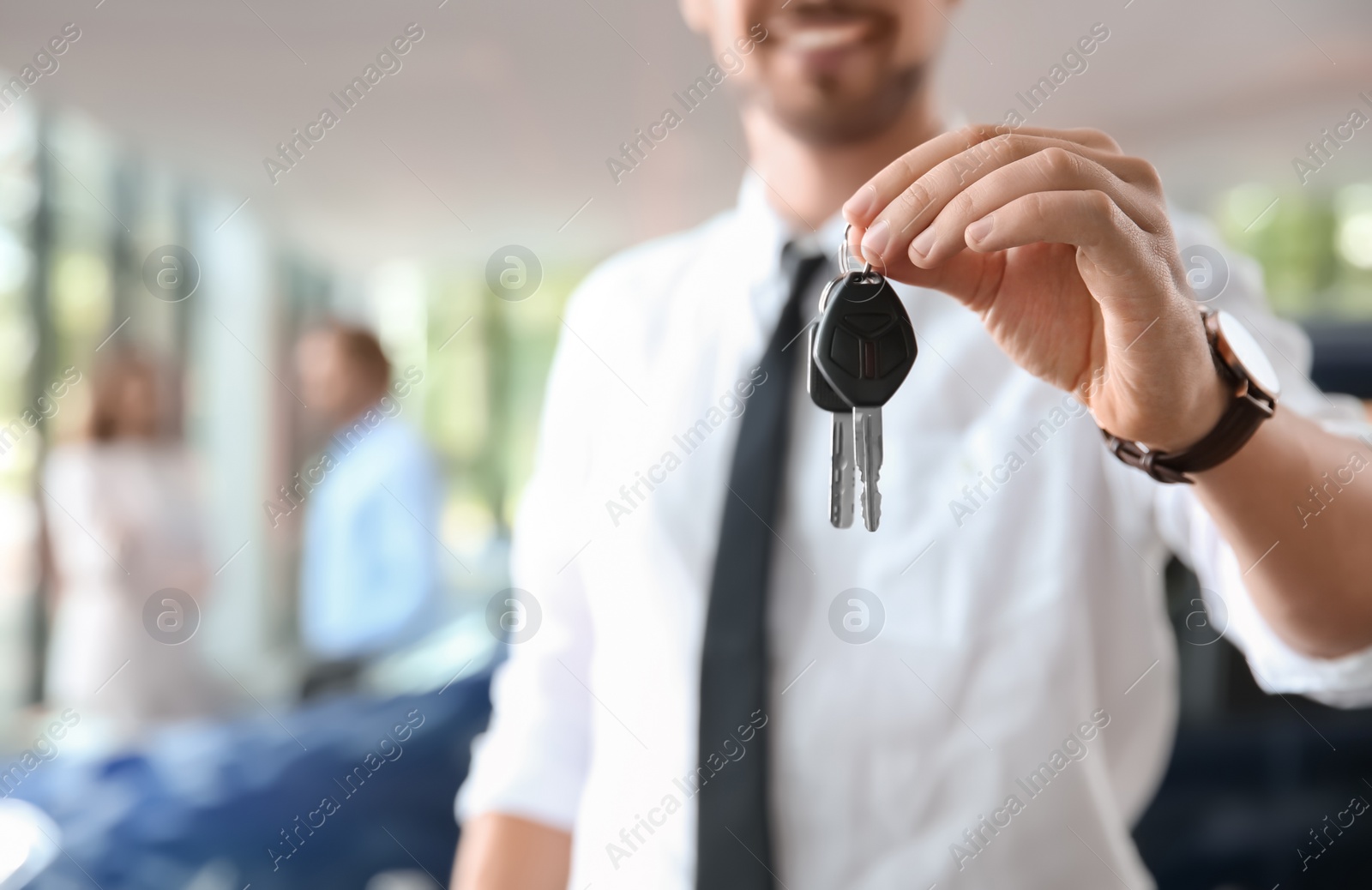 Photo of Salesman with car keys in auto dealership, closeup