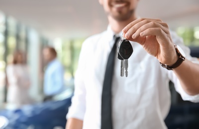 Photo of Salesman with car keys in auto dealership, closeup
