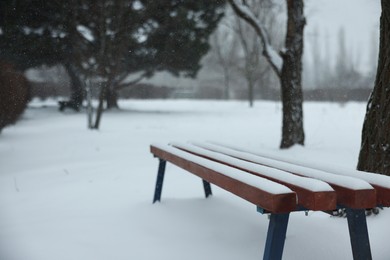 Photo of Bench covered with snow in city park