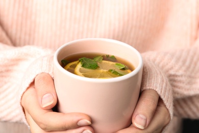 Photo of Woman holding cup with hot tea, closeup