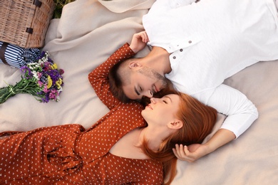 Photo of Happy young couple lying on picnic blanket, above view