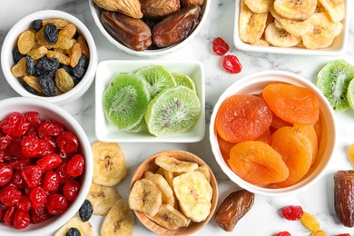 Bowls with different dried fruits on marble background, flat lay. Healthy lifestyle