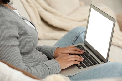 Photo of Woman using laptop on sofa indoors, closeup
