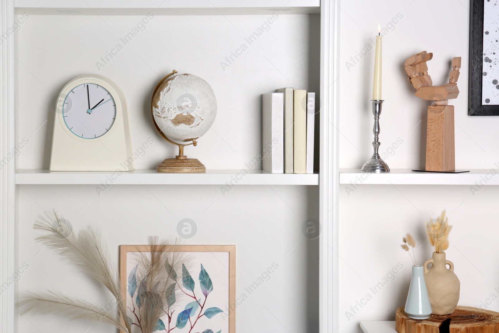 Photo of White shelves with books, globe and different decor indoors. Interior design