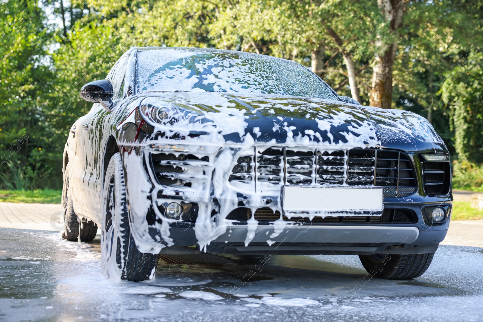 Photo of Auto covered with cleaning foam at outdoor car wash