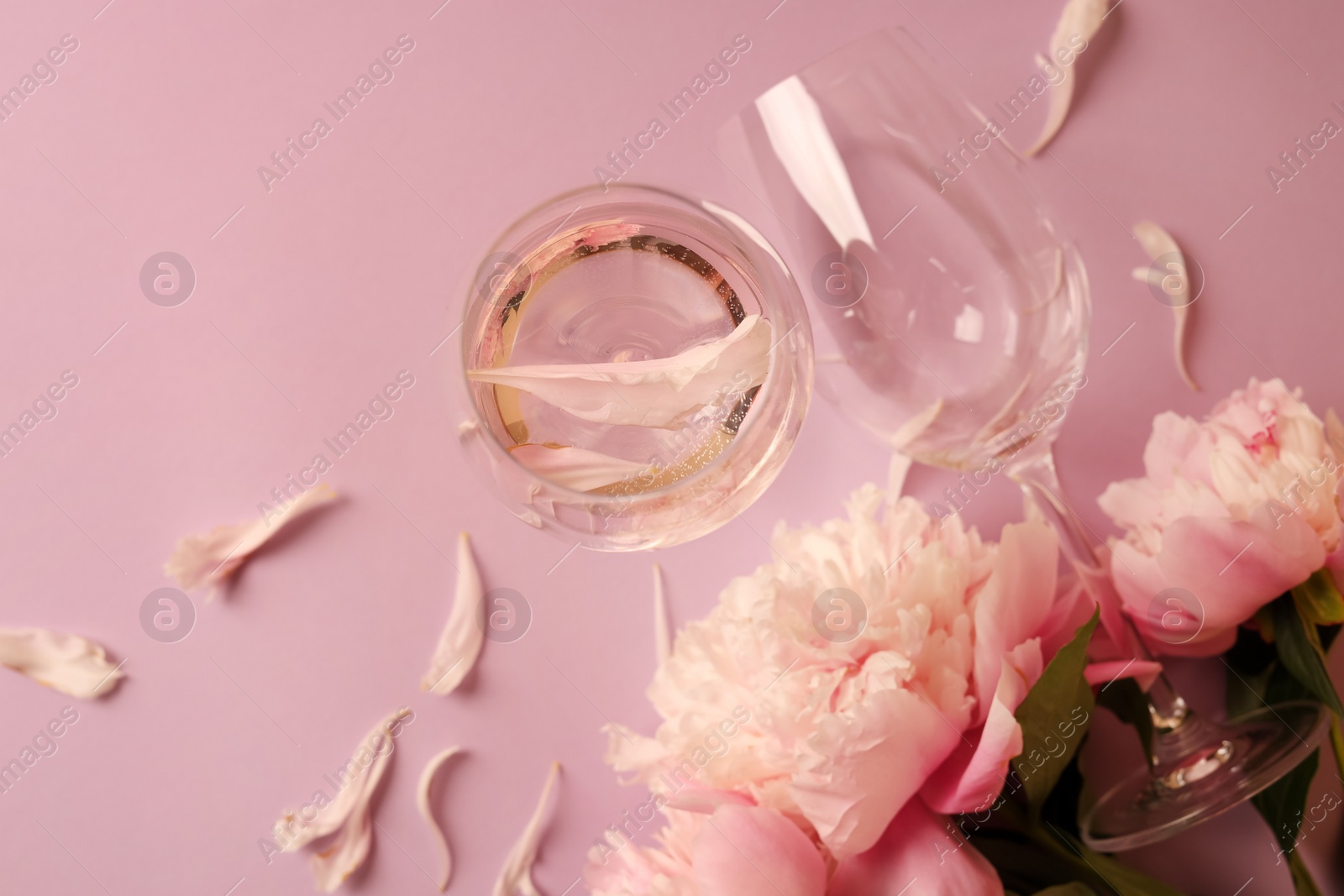 Photo of Flat lay composition with rose wine, glasses and beautiful peonies on pink background