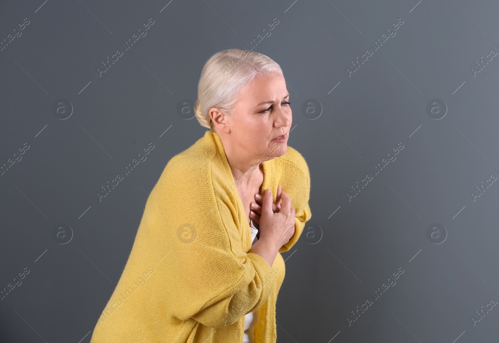 Photo of Mature woman having heart attack on color background