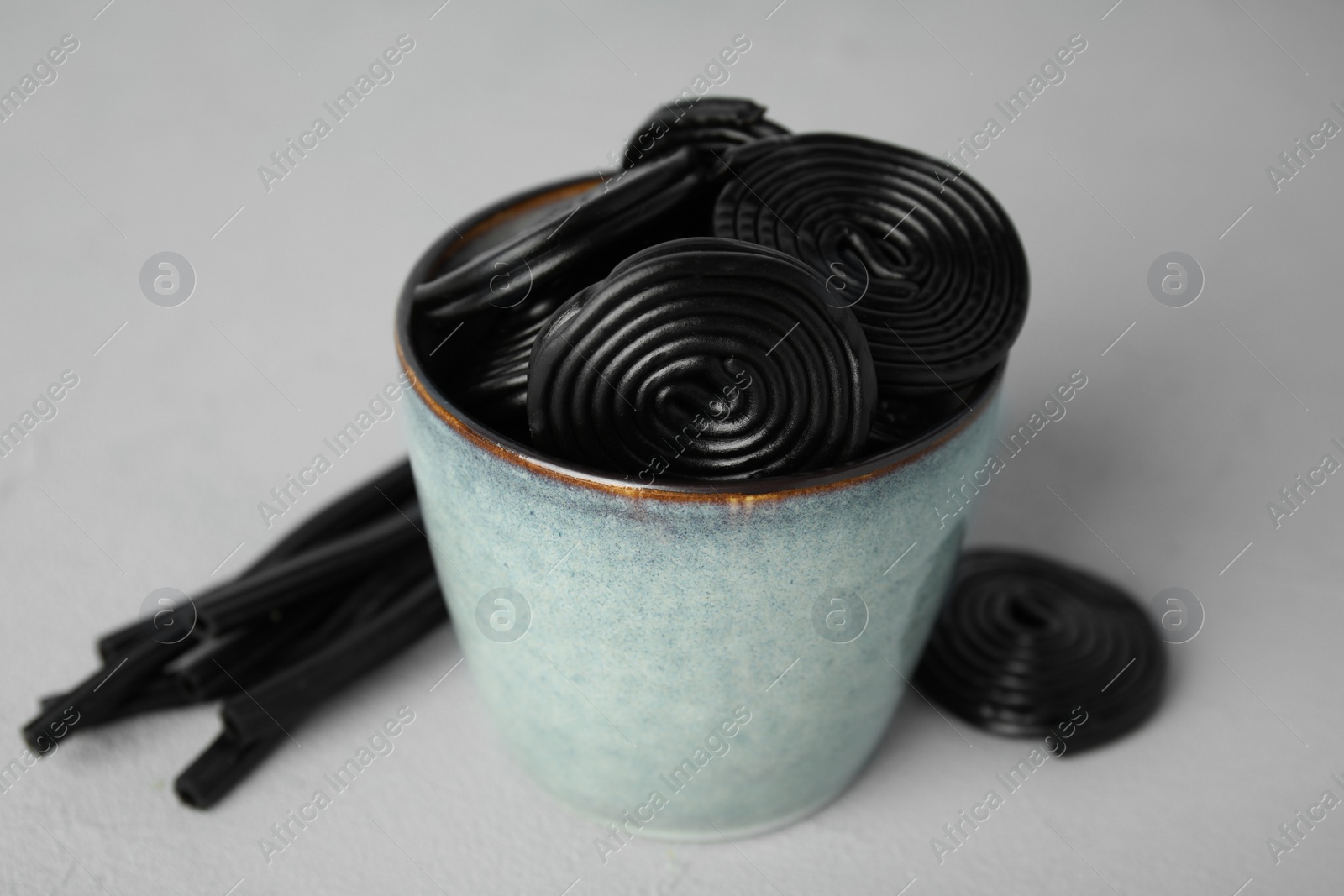 Photo of Tasty black liquorice candies on grey table, closeup