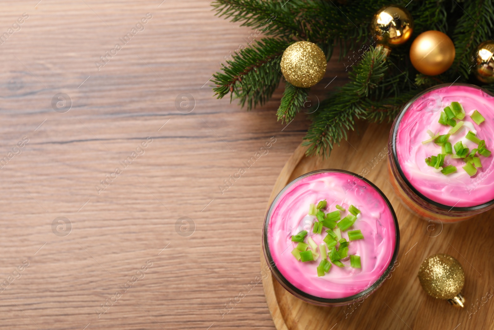 Photo of Glass jars of herring under fur coat and Christmas decor on wooden table, flat lay with space for text. Traditional Russian salad