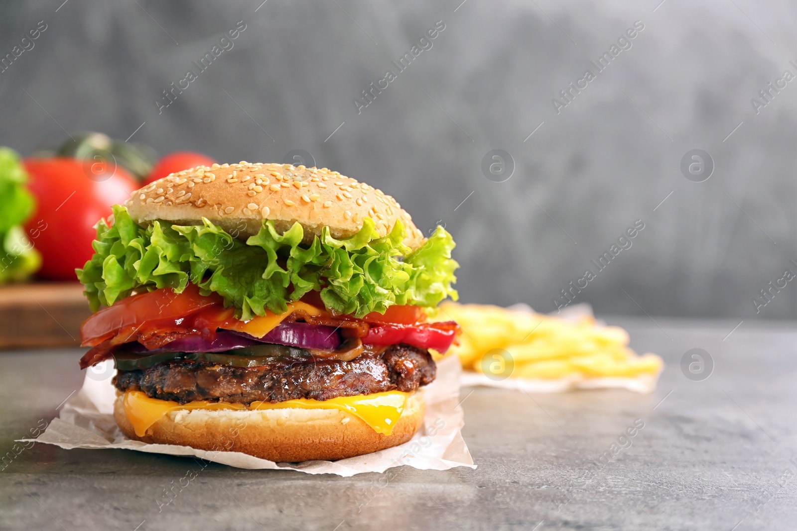 Photo of Tasty burger with bacon on grey table. Space for text