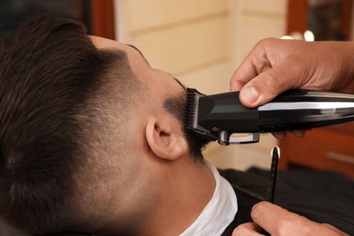 Photo of Professional hairdresser working with client in barbershop, closeup