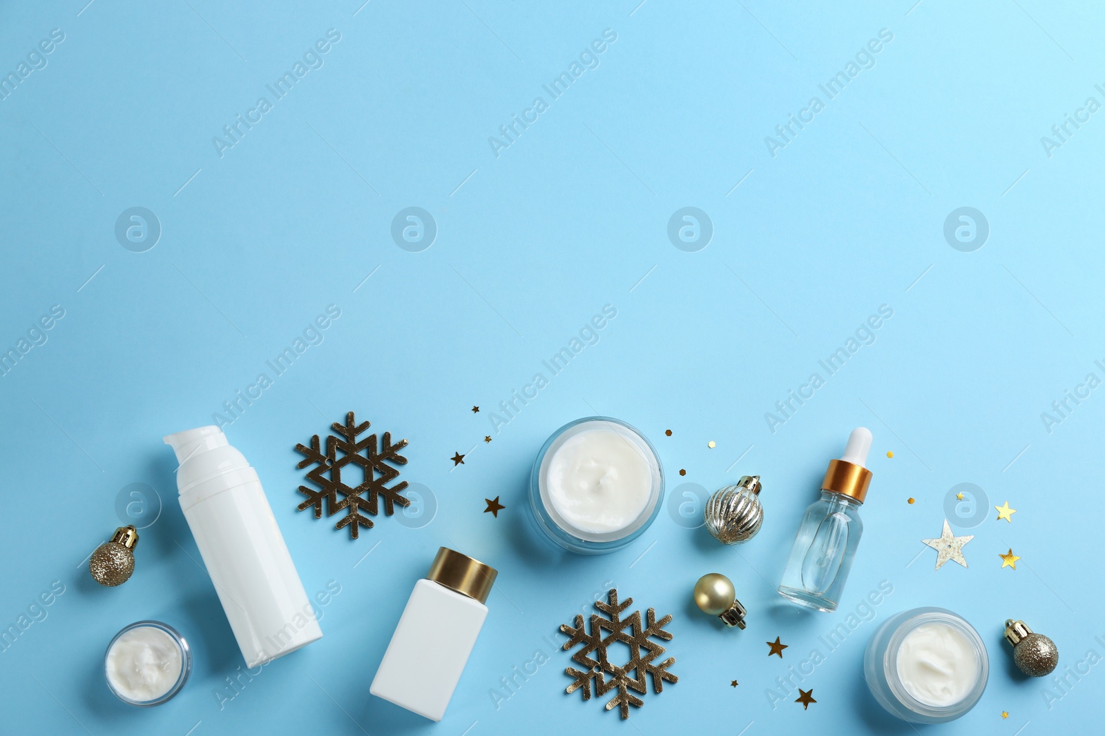 Photo of Flat lay composition with different cosmetic products on light blue background, space for text. Winter care