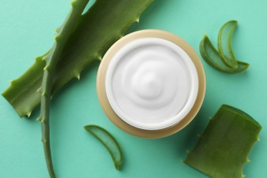 Jar of natural cream and aloe leaves on green background, flat lay