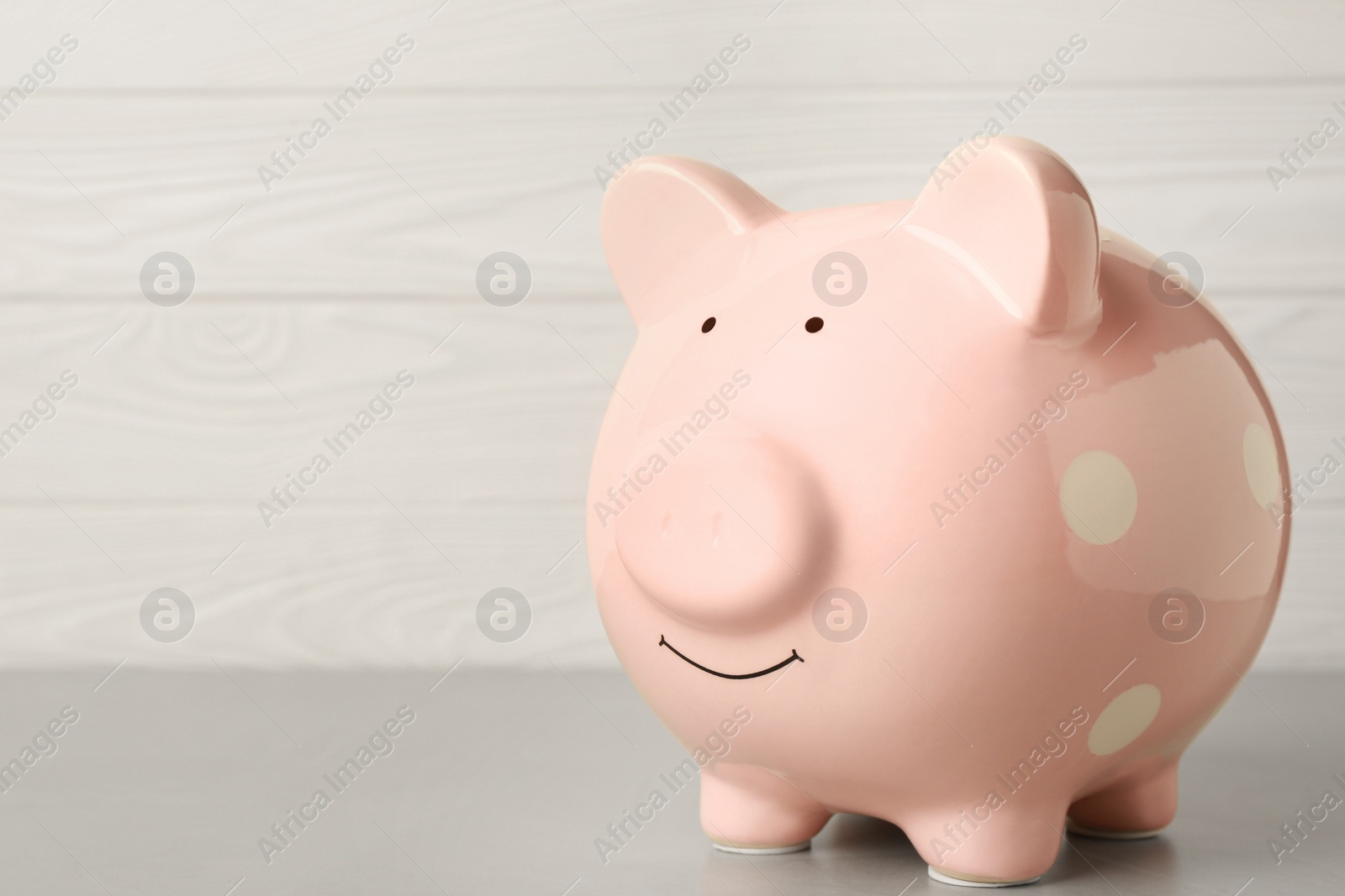 Photo of Ceramic piggy bank on light grey table. Space for text