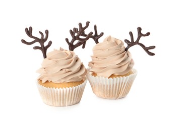 Photo of Delicious Christmas cupcakes with chocolate reindeer antlers on white background