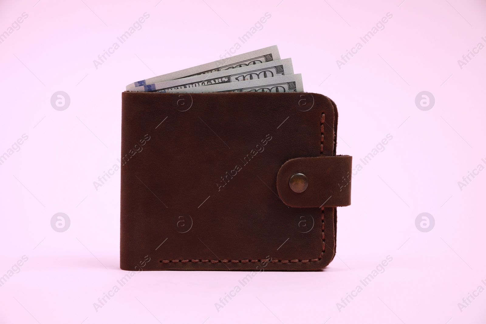 Photo of Stylish brown leather wallet with dollar banknotes on pink background