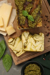 Photo of Freshly baked pesto bread with ingredients on grey table, flat lay