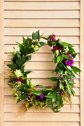 Beautiful wreath made of flowers and leaves hanging on wooden folding screen