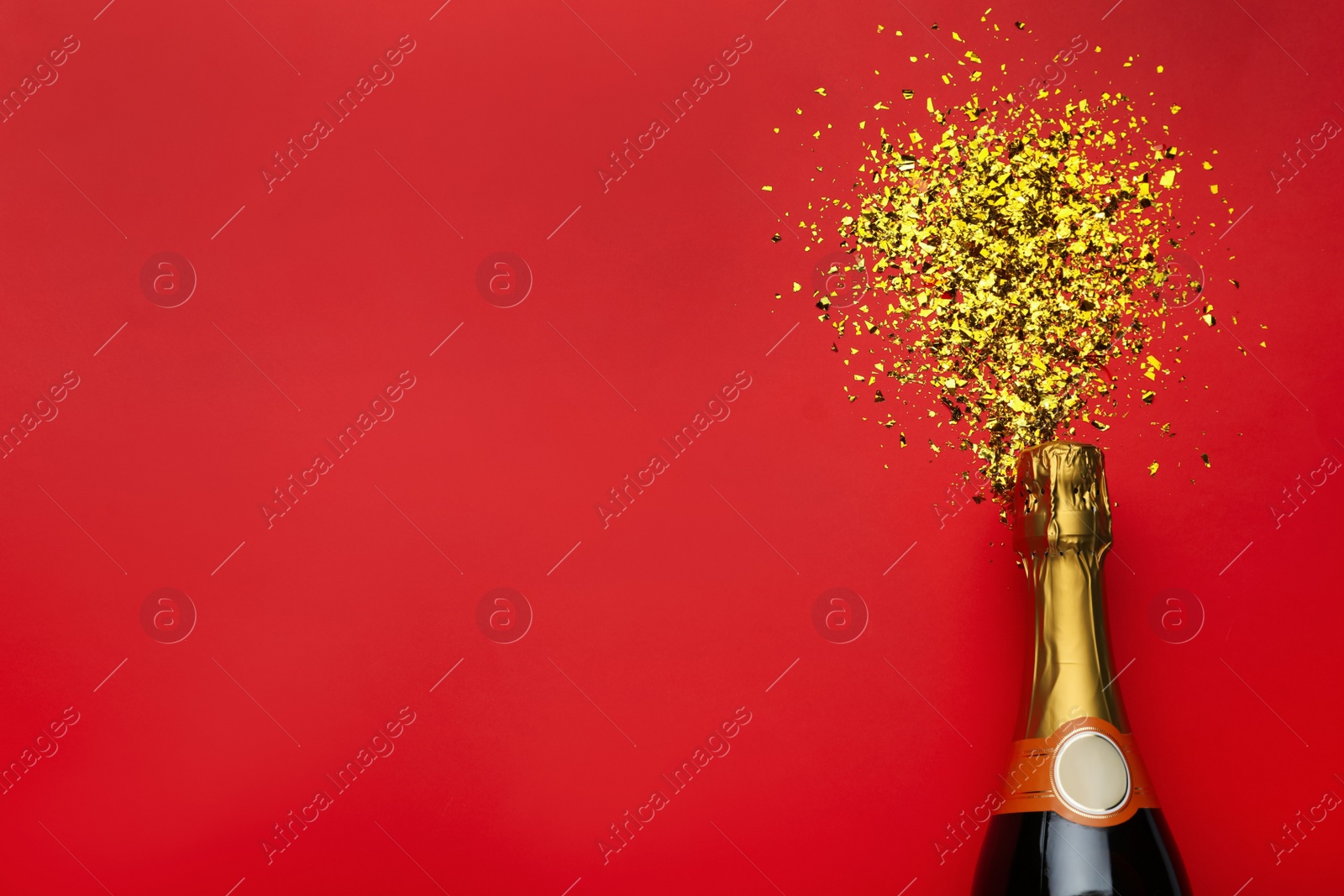 Photo of Flat lay composition with confetti and bottle of champagne on red background. Space for text